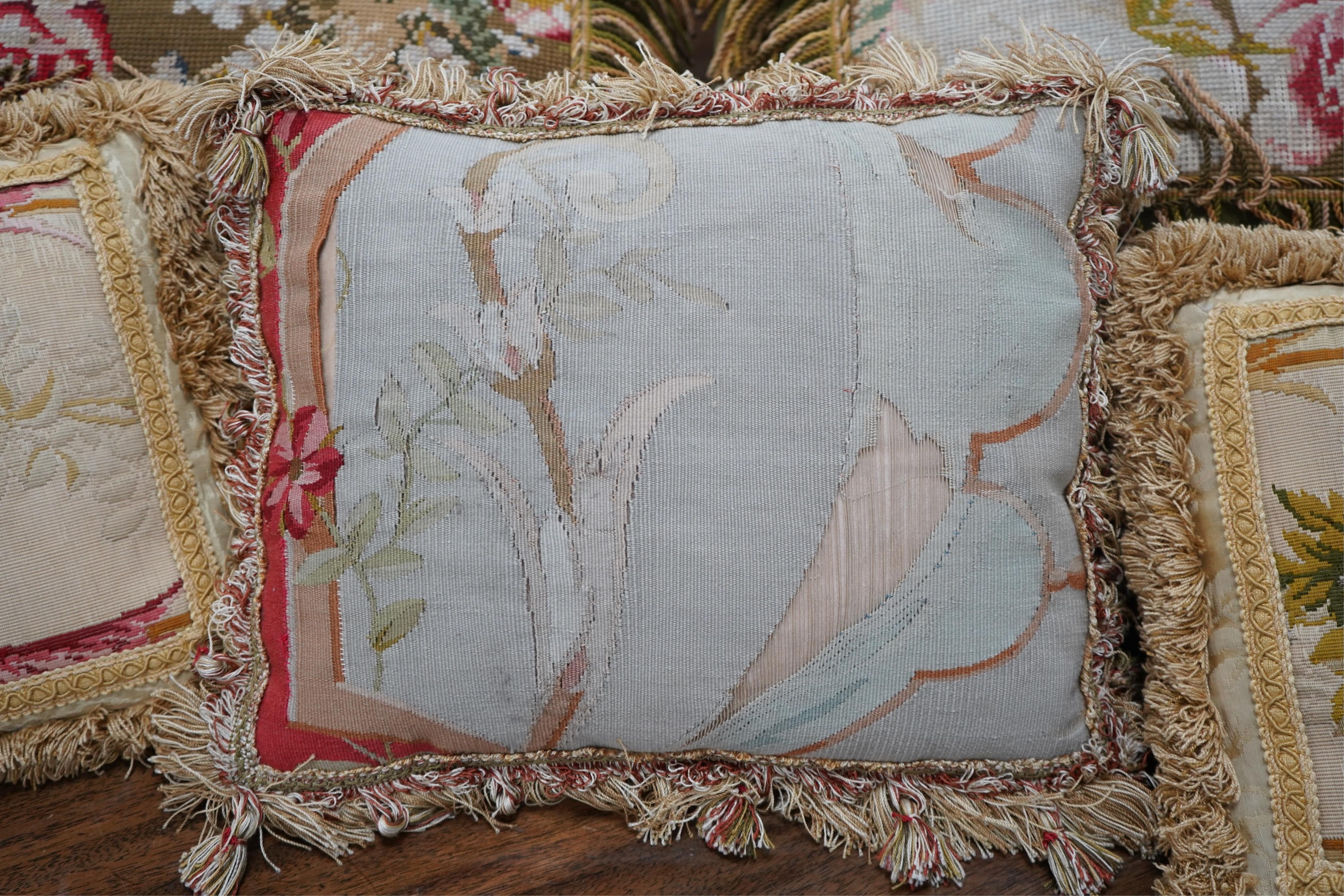 Seven 19th century cushions. Three Aubusson tapestry cushions and two machine Aubusson cushions, together with two floral wool worked cushions, all with decorative fringing. Largest 40cm x 45cm. condition - three are wor